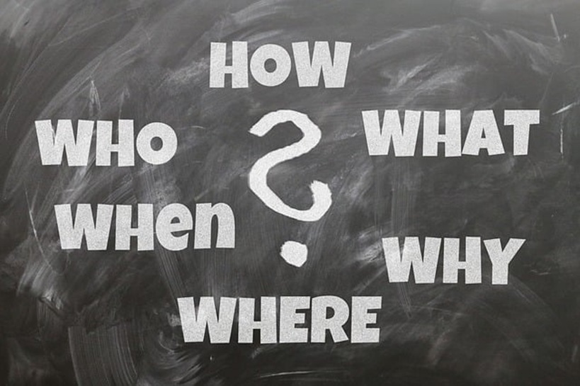 黒板に書かれた5W1H（Who, What, When, Where, Why, How）と疑問符。お客様のすべての疑問を解決するイメージ。